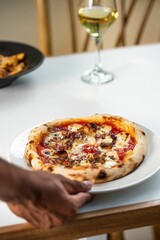 Person putting a plate of delicious pizza on the table