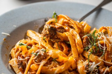 Bowl of delicious fresh pasta with meat, sauce, and cheese on the table