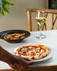 Person putting a plate of delicious pizza on the table
