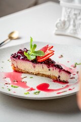 Piece of delicious berry cheesecake on a plate on the table
