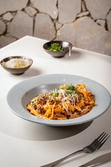 Bowl of delicious fresh pasta with meat, sauce, and cheese on the table