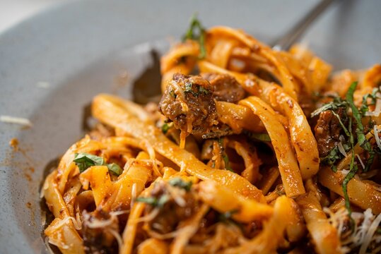 Bowl of delicious fresh pasta with meat, sauce, and cheese on the table