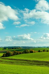 Stunning rural landscape with a green field and a blue sky with white clouds. Bavaria, Haimhause.