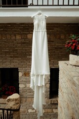 the white wedding dress hanging in a beutiful room with stone walls