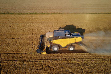 Obraz premium Harvesting machine working at agricultural field. Combine harvester collecting golden wheat field. Harvest reaping season
