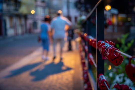 Middle-aged couple walking along a fence decorated with heart-shaped locks