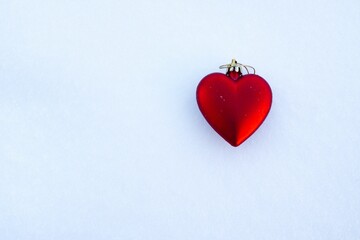 Red heart-shaped Christmas tree ornament on a white surface