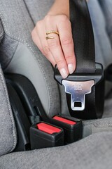 Vertical of a female hand holding a seatbelt with the inscription 