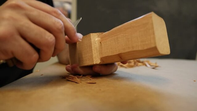 Closeup video of wood carving process of a human figure with a knife