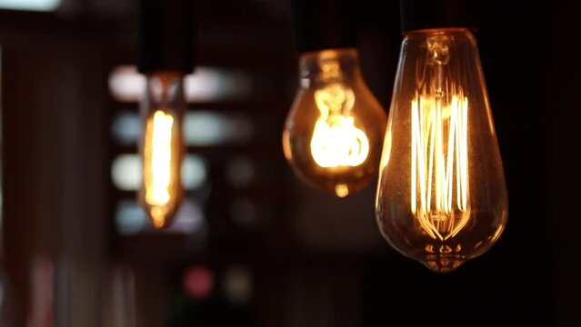 Closeup video of retro edison bulbs with yellow light on a blurred background