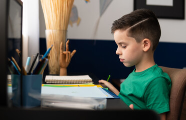 Young boy does homework at the table in the room
