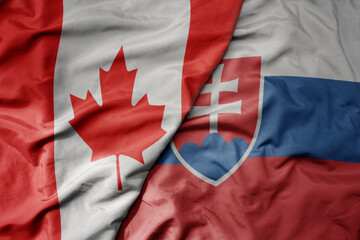 big waving realistic national colorful flag of canada and national flag of slovakia .
