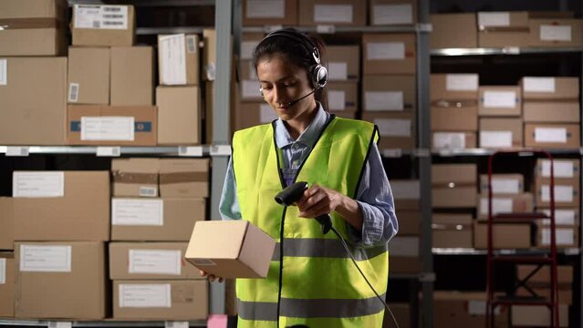 Woman wearing headset uses barcode reader in a warehouse checking parcels