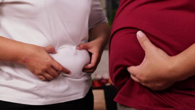 Obese men and women use their hands to hold their belly at the same time. Weight loss concept. health care