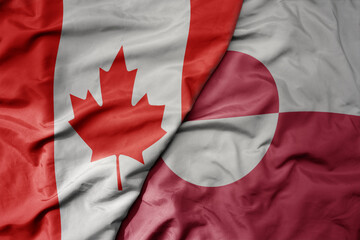 big waving realistic national colorful flag of canada and national flag of greenland .