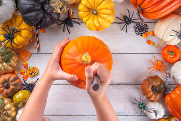 Preparation for Halloween with carving cutting pumpkin Jack Lantern. Female, woman and kids hands in frame, decorate, drawing and carves scary Halloween party Pumpkin top view copy space