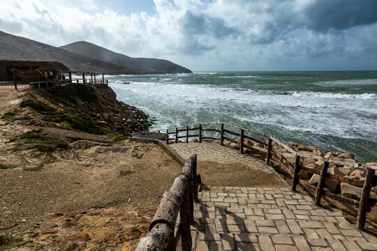 Wooden walkway guides the way to the sandy beach of Bizerte, Tunisia, lined with a set of stairs