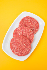 Three raw red meat burgers for hamburgers of minced ground beef on dish