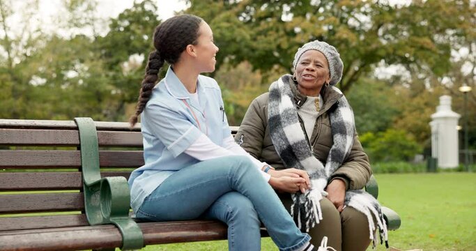 Nurse, happy and talking with old woman on park bench for retirement, elderly care and conversation. Trust, medical and healthcare with african patient and caregiver in nature for rehabilitation