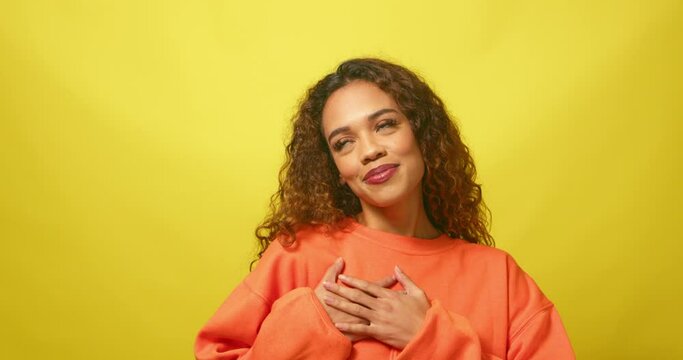 Beautiful woman puts hands on heart, infatuated and dreaming of crush, studio