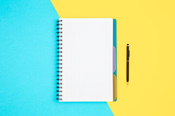 Open spiral notepad on blue yellow background, flat lay.