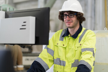 Male engineer worker working with desktop computer in industry factory. Male technician using computer control and maintaining machine in the factory