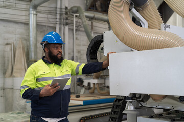 Male engineer worker using digital tablet inspecting quality CNC machine in industry factory. Male technician wear safety uniform working checking and maintaining machine in factory