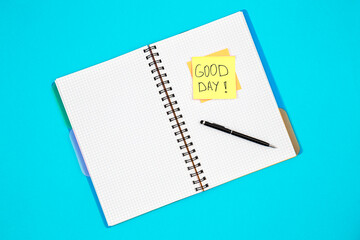 Notepad and paper reminder with the inscription Good day on a blue background.