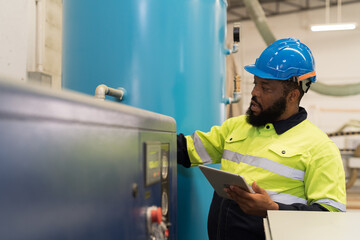 Factory male engineer worker working and using digital table checking tank of air compressor in...