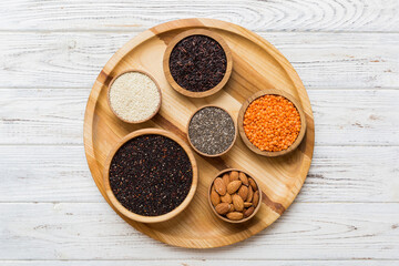 Various superfoods in smal bowl on colored background. Superfood as rice, chia, quinoa, lentils, nuts, sesame seeds, almonds. top view