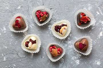 chocolate sweets in the form of a heart with fruits and nuts on a colored background. top view with space for text, holiday concept