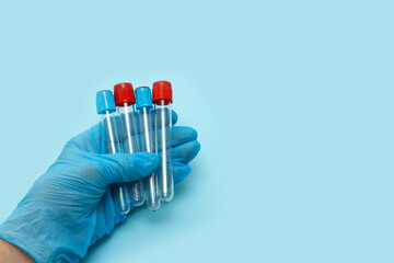 empty test tubes in the hand of a medic in a glove on a blue background with copy space