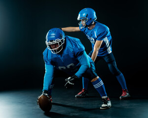 Two American football players are ready to start the game on a black background. 