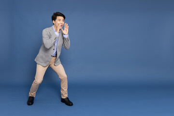 Young Asian business man shout loudly isolated on blue background, Speaker and announce concept