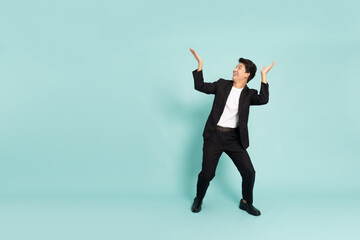 Shocked Asian businessman and looking up on top isolated on green background