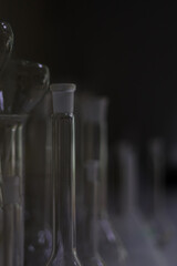The upper part of the measuring flask in a row of chemical dishes on a dark background
