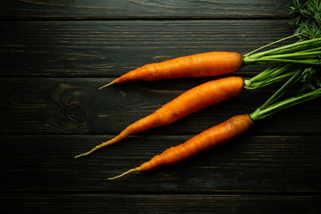 Three fresh and sweet carrots on a black kitchen table are ready to be added to a meal. Carrot diet...