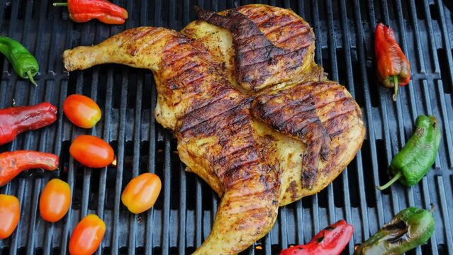 Cooking fried roast Chicken Tabaka on grill with vegetables.Tobacco chicken