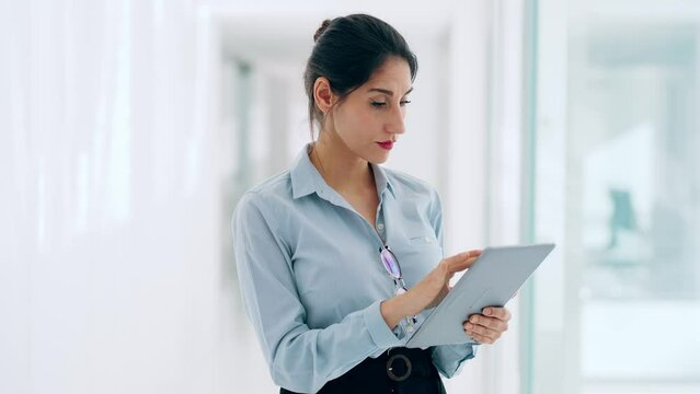 Video of elegant attractive businesswoman working with digital tablet while standing in hallways at a modern startup