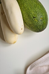 Raw eggplant, zucchini on a white table. Simple vegetable minimalistic background. Farmers local market. Healthy organic harvest. Gardening, farming as a hobby. Culinary. Ingredients for vegan dishes.