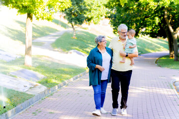 Grandparents walking in the park with their baby grandson