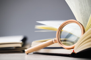 Closeup magnifying glass lean on the page of the opened book, research information, glossary,...