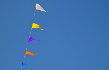 Multicolored triangular small flags to celebration party against blue sky.Street holiday concept for design.Selective focus.

