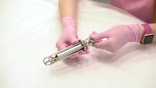 Close-up of the hands of a female doctor gynecologist in pink medical gloves, holding metal tools, nozzles for Fotona laser gynecology. copy space. The concept of laser gynecology.
