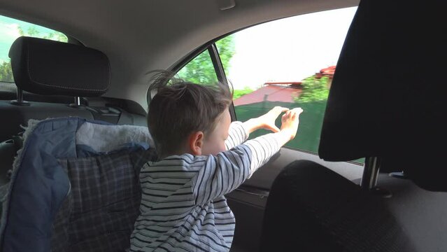 Little boy hands out of car window feeling the wind while travelling
