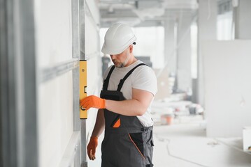 Fototapeta na wymiar Man holding level against plasterboard, interior drywall. Attic renovation
