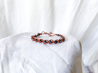 Handmade wire copper bracelet with metallic beads. Wire wrapped accessories, white background.
