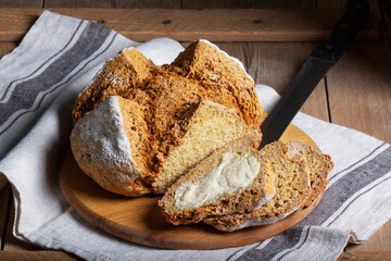 Traditional Irish soda bread made from whole grain and rye flour on a wooden table. Rustic style.
