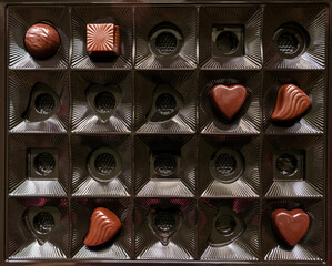 A square box with a small amount of chocolates. An almost empty box of chocolates