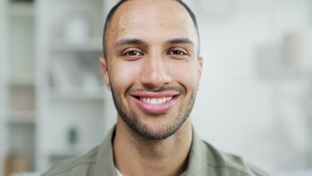 Portrait happy smiling handsome man looking at camera in the living room at home. Young adult mixed race male joyful positive in casual shirt indoors satisfied contented face expression indoor closeup